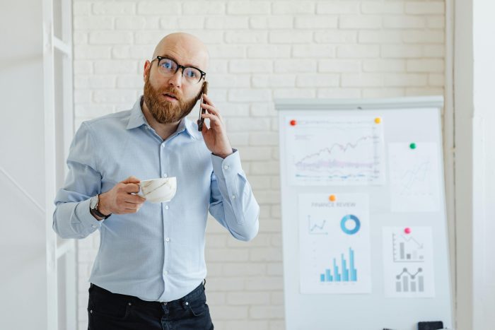 white man in office talking on phone holding cup